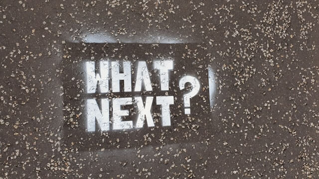 Spray painted white words on concrete read: 'WHAT NEXT?'