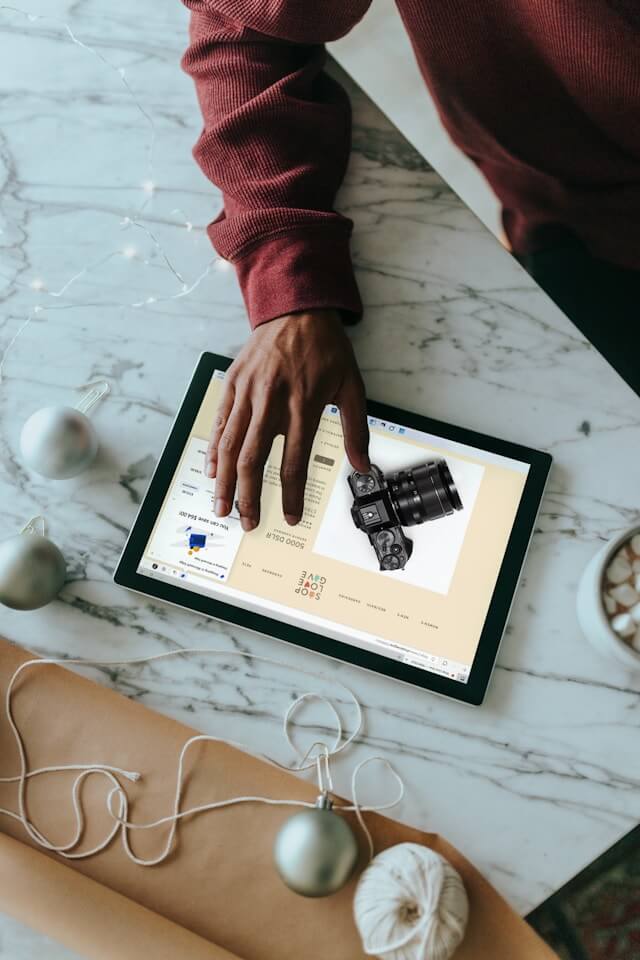 A top down view of a man shopping for a camera on his ipad.