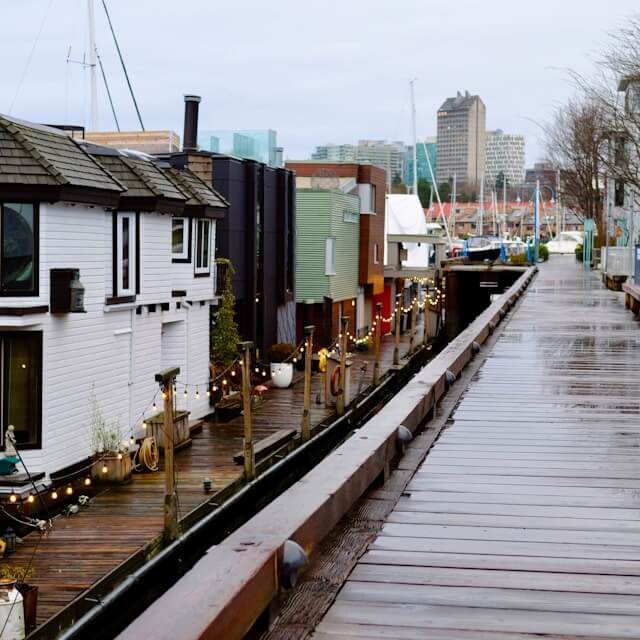An empty boardwalk on a rainy day beside a group of houseboats at the Lonsdale Quay Marina.