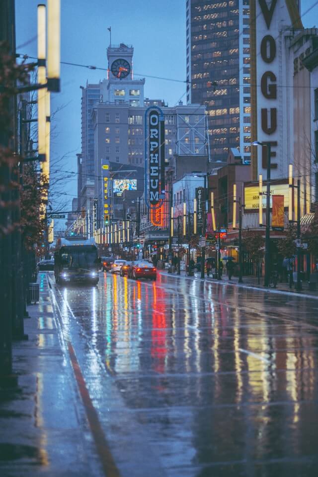 Granville street on a gloomuy and rainy day. The city lights reflect in the pools of water on the main street.