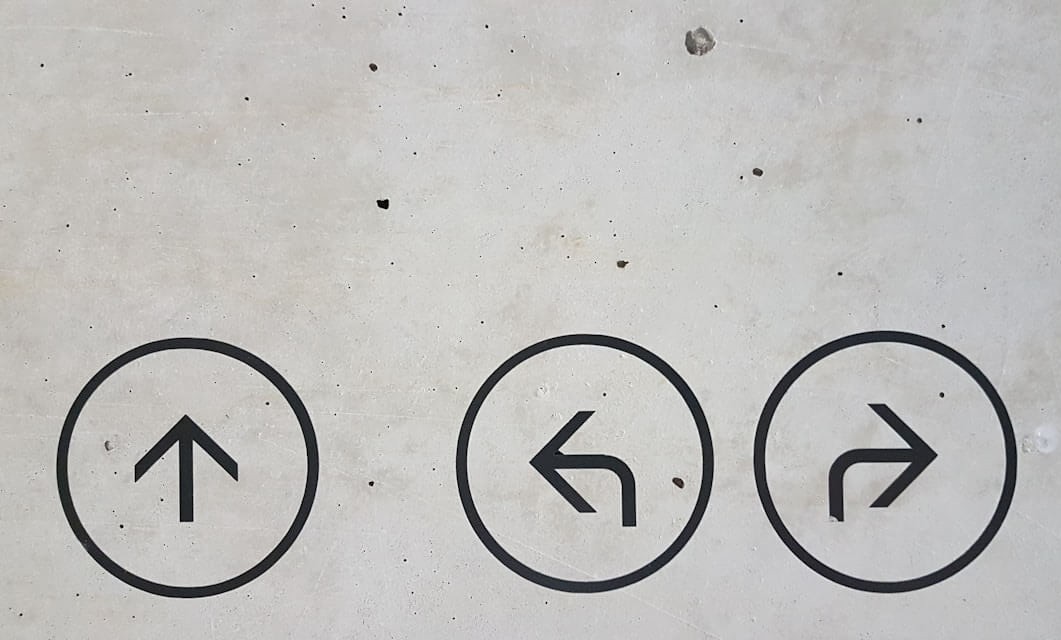 Arrows painted on a concrete wall point in every direction.