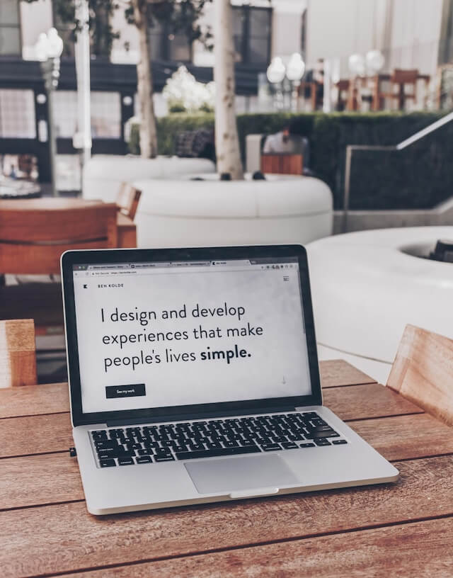 An open laptop with a message on the screen that reads 'I design and develop experiences that make people's lives simple'