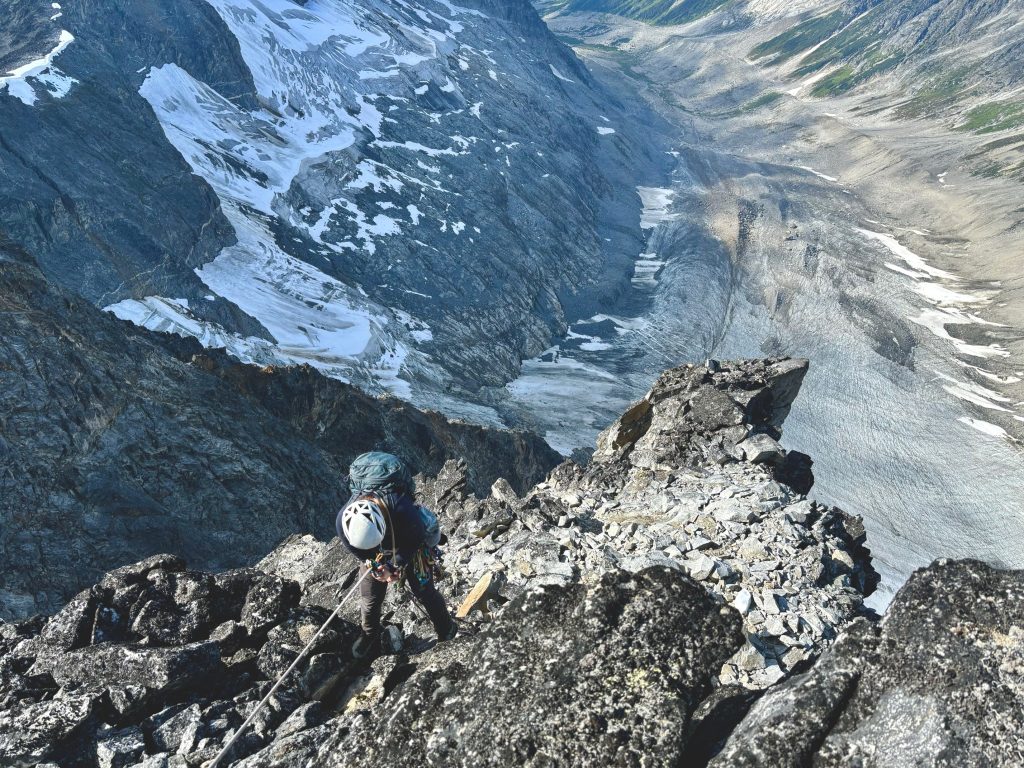 A photo of a woman rapelling down a mountain on a rope.