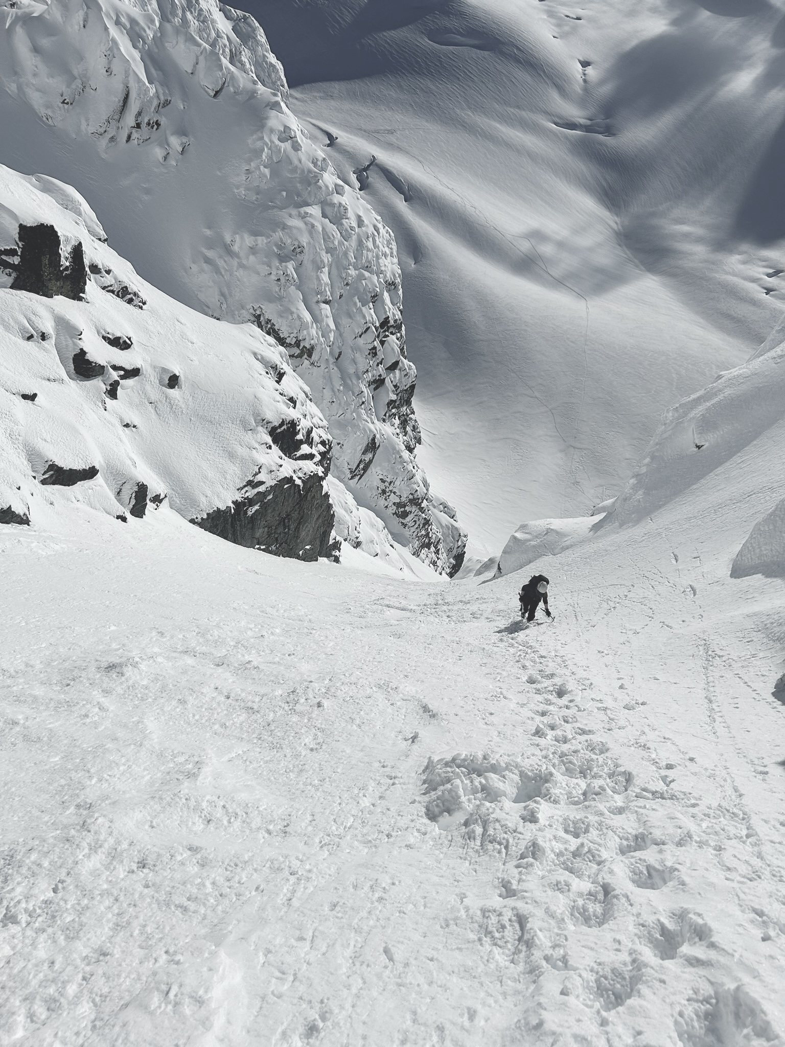 A photo of a woman climbing up a steep snowy slope.